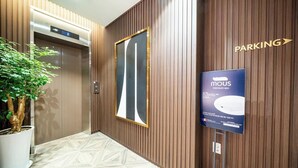 Un vestíbulo de hotel con un panel de madera, un espejo grande, una planta en maceta y un letrero para una cama premium.