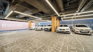 Un estacionamiento con varios coches blancos aparcados bajo techos iluminados.
