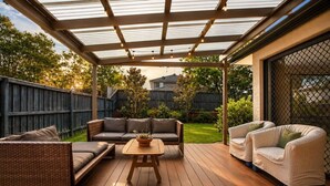 Eine Terrasse im Freien mit Holzdeck, einem überdachten Sitzbereich mit einer Couch und Stühlen sowie einem Tisch mit einer Pflanze.