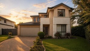 Ein modernes, zweistöckiges Haus mit Garage, gepflegtem Rasen und Auffahrt aus Ziegelsteinen.