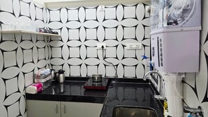 Et køkken med et mønstret backsplash, en vanddispenser, en vask og en bordplade med diverse genstande.