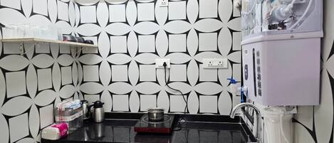 Une cuisine avec un crédence décorée, un distributeur d’eau, un évier et un plan de travail sur lequel se trouvent divers objets.