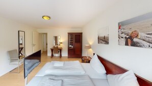 Una camera d'albergo con un letto, comodini, una scrivania con una sedia, uno specchio, un armadio e un quadro appeso al muro.