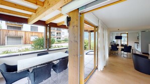 Una cucina moderna con zona pranzo, travi in legno al soffitto e vista sull'esterno.