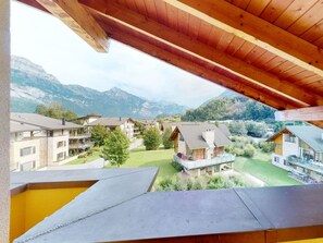 A view from a balcony with a wooden ceiling, overlooking a residential area with houses and mountains in the background. - Walensee House & Apartments, (Unterterzen), by Interhome (Unterterzen)