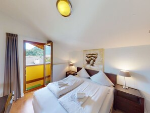 A hotel room with a bed, two bedside lamps, a painting on the wall, and a view through a door. - Walensee House & Apartments, (Unterterzen), by Interhome (Unterterzen)