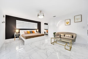 A modern bedroom with a bed, a sofa, a coffee table, and a chandelier. - Villa Bellavista, Tropical 5BR Oasis with Private Pool (NE)