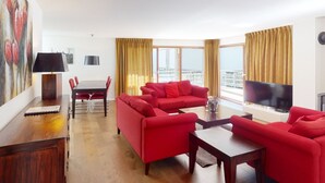 A modern living room with a red sofa set, a dining table, and a TV. - Walensee House & Apartments, (Unterterzen), by Interhome (Unterterzen)