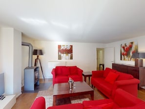 A living room with red sofas, a wooden coffee table, a fireplace, and artwork on the walls. - Walensee House & Apartments, (Unterterzen), by Interhome (Unterterzen)