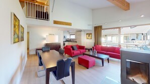 A modern living room with a dining area, red sofas, a fireplace, and a kitchen in the background. - Walensee House & Apartments, (Unterterzen), by Interhome (Unterterzen)
