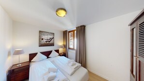 A hotel room with a bed, bedside tables, a lamp, a painting, a window with curtains, and a wardrobe. - Walensee House & Apartments, (Unterterzen), by Interhome (Unterterzen)