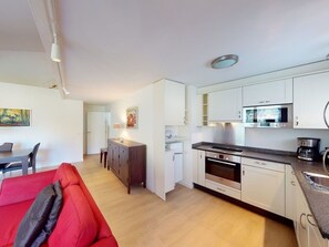 A modern kitchen with white cabinets, a built-in oven, and a microwave.
