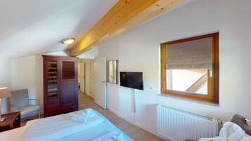 Ein Hotelzimmer mit einem großen Bett, einem Fernseher, einem Fenster mit Blick, einer Holzbalkendecke und einer Heizung.