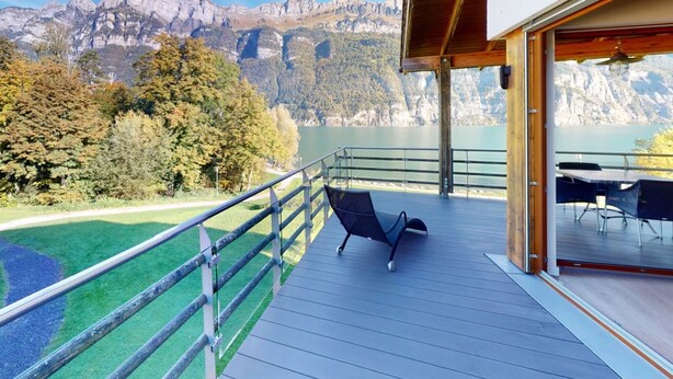 A balcony with a view of mountains and a lake, a chair, and a table with chairs. - Walensee House & Apartments, (Unterterzen), by Interhome (Unterterzen)