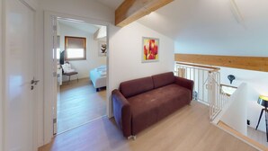 An interior with a brown sofa, a painting, and a staircase. - Walensee House & Apartments, (Unterterzen), by Interhome (Unterterzen)