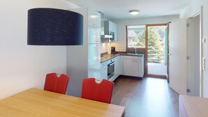 Una cocina moderna con armarios blancos, una mesa de comedor de madera y sillas rojas.