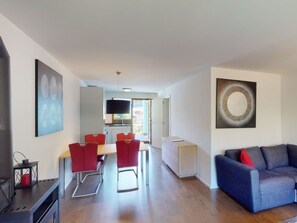 A modern living space with a dining area, a kitchen, and a seating area with a sofa.