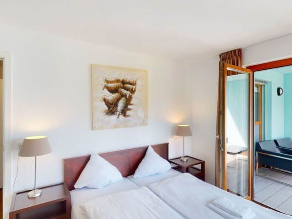 A hotel room with a bed, two bedside tables, a lamp, and a painting on the wall.