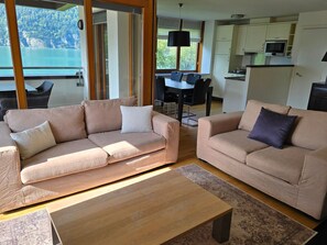 A modern living room with two sofas, a coffee table, and a dining area with a table and chairs.