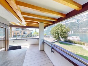 A balcony with a view of a lake and mountains, wooden beams, and a table.