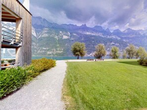 A pathway leading to a building with a mountain view, benches, and a grassy area.