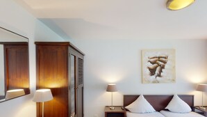 Ett hotellrum med en säng, sängbord, en garderob, en tavla på väggen och en taklampa.