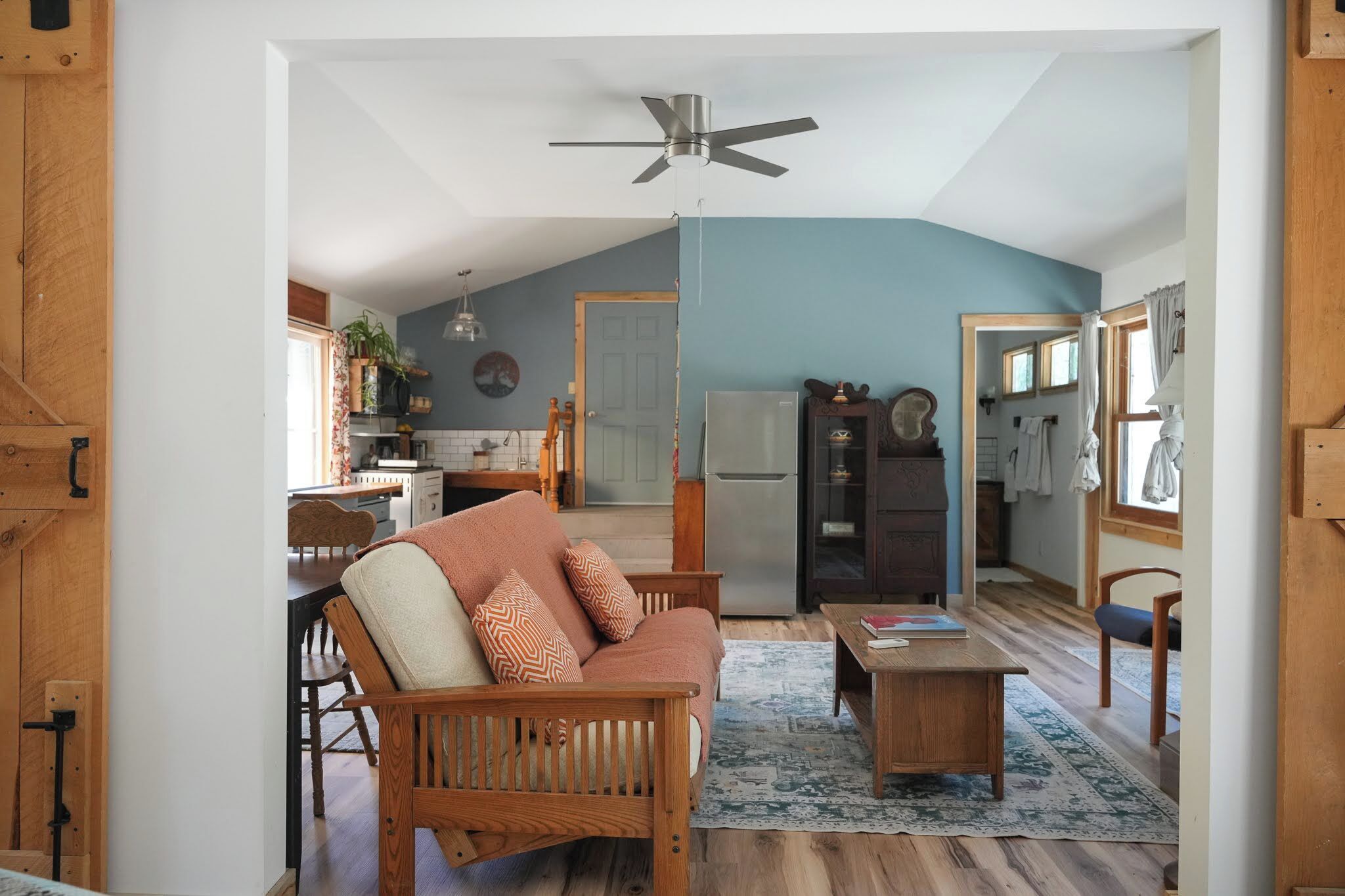 Uma sala de estar acolhedora com sofá, mesa de centro e ventilador de teto.
