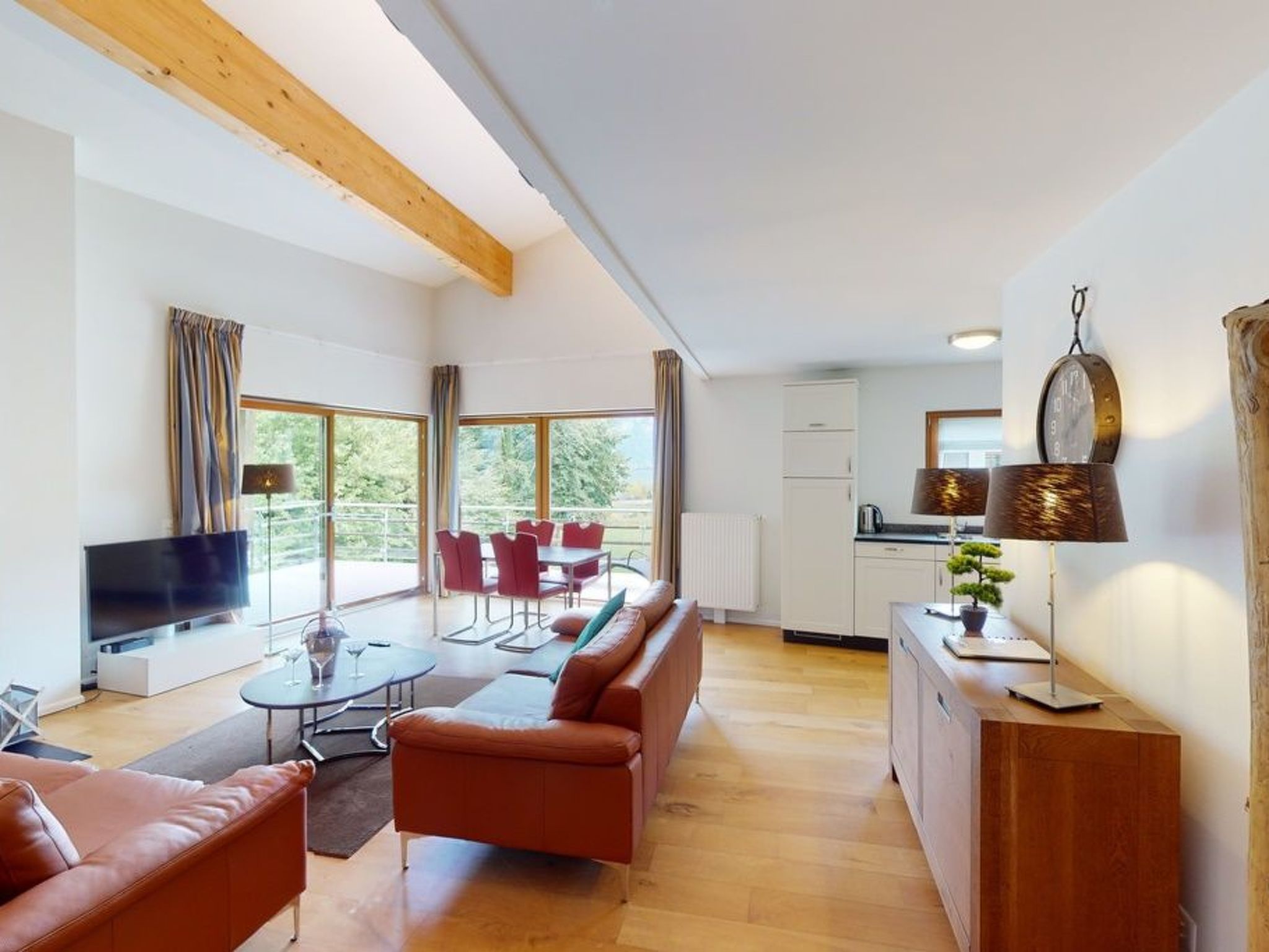 A modern living room with a sofa, TV, and dining area.