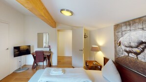 Ein Hotelzimmer mit einem Bett, einem Schreibtisch, einem Fernseher, einem Gemälde und einer Lampe.