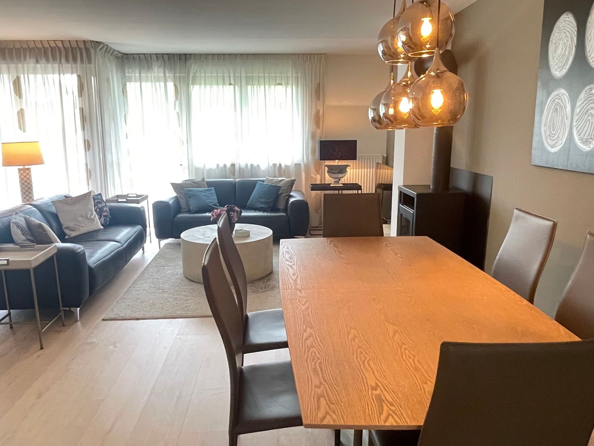 Una sala de estar moderna con una mesa de comedor, sofás y una chimenea.