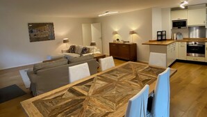 Uma sala de estar moderna com mesa de jantar, conjunto de sofá e cozinha equipada.