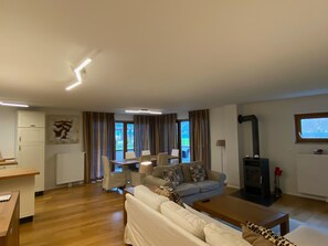 Un salon comprenant un canapé, une table basse, une cheminée et un coin repas avec des chaises et une table.