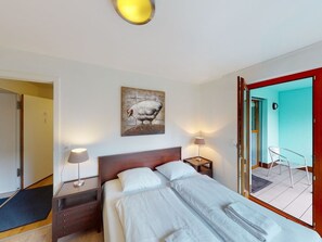 A hotel room with a bed, bedside lamps, a painting, and a door leading to a balcony. - Walensee House & Apartments, (Unterterzen), by Interhome (Unterterzen)