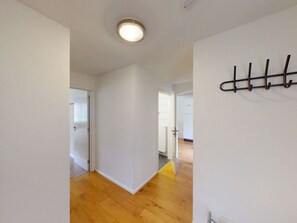 A hallway with wooden flooring, white walls, and a ceiling light. There is a door on the left and a coat rack on the right. - Walensee House & Apartments, (Unterterzen), by Interhome (Unterterzen)