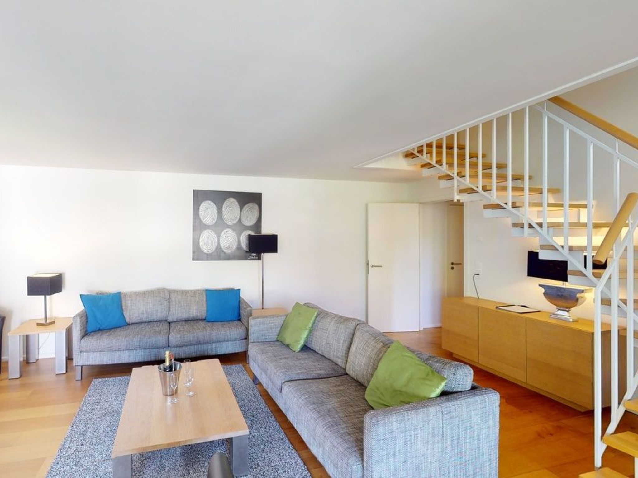 Un salon moderne comprenant un canapé, une table basse et un escalier.