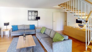 Een moderne woonkamer met een bank, een salontafel, een trap en een deur.