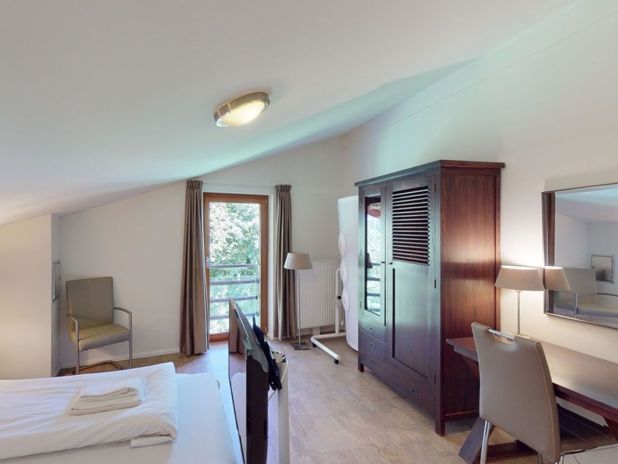 Une chambre d’hôtel équipée d’un lit, d’un bureau, d’une chaise, d’une armoire et d’un radiateur.