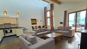 Een moderne woonkamer met banken, een salontafel en een keuken met kasten en een fornuis.