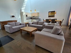 A modern living room with sofas, a coffee table, and a dining area with chairs and a table.