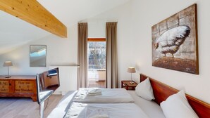 Een hotelkamer met een bed, een schilderij, een houten kast en een raam met gordijnen.