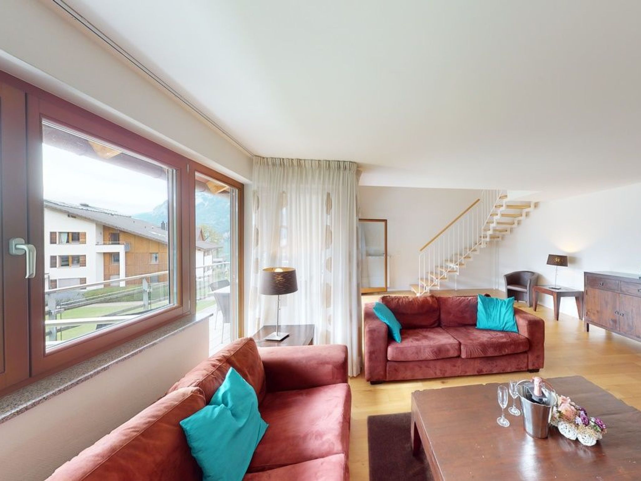 A modern living room with a sofa set, a coffee table, and a staircase leading to an upper floor.