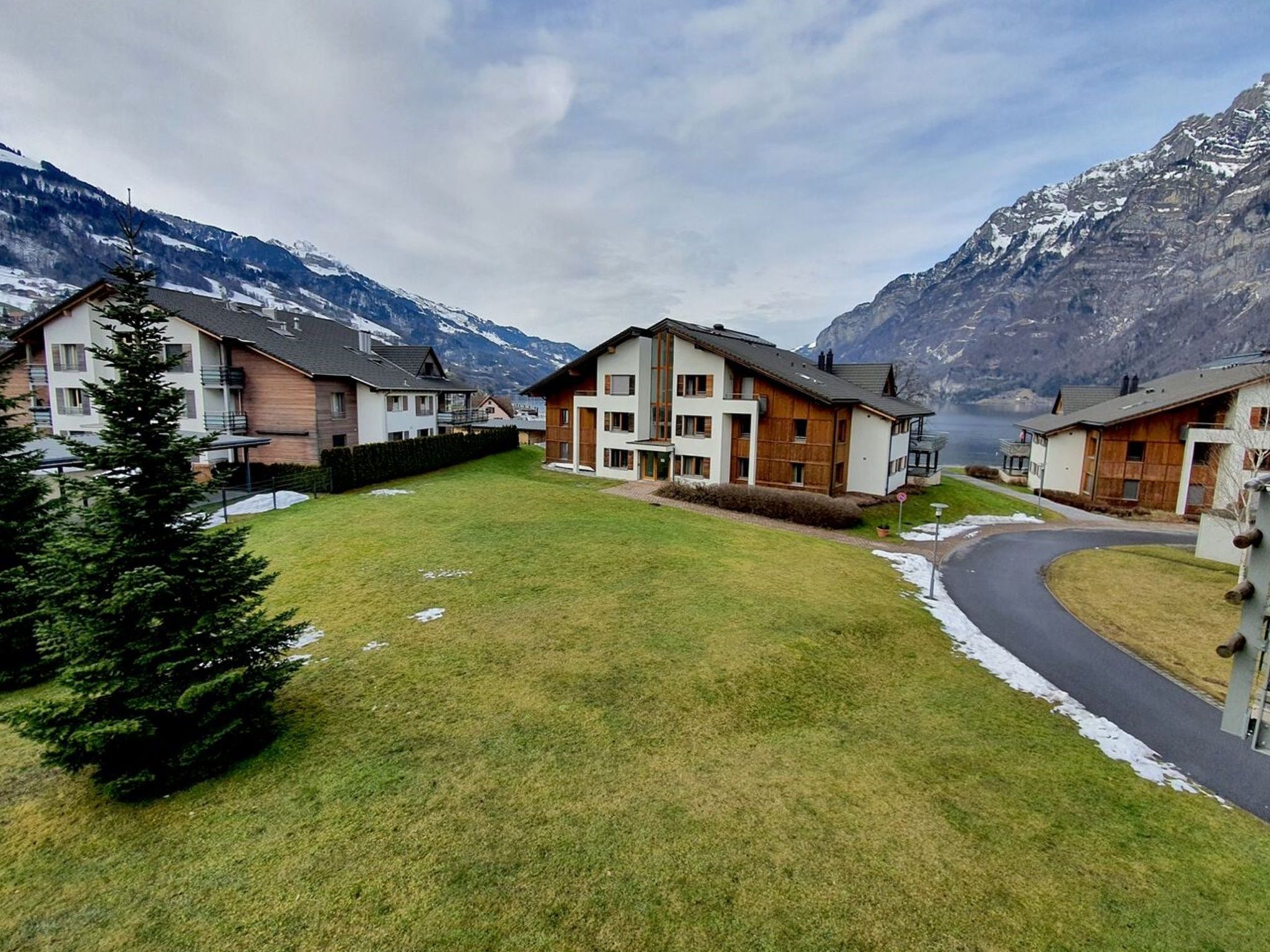 Un barrio residencial con casas modernas, un césped bien cuidado y montañas al fondo.