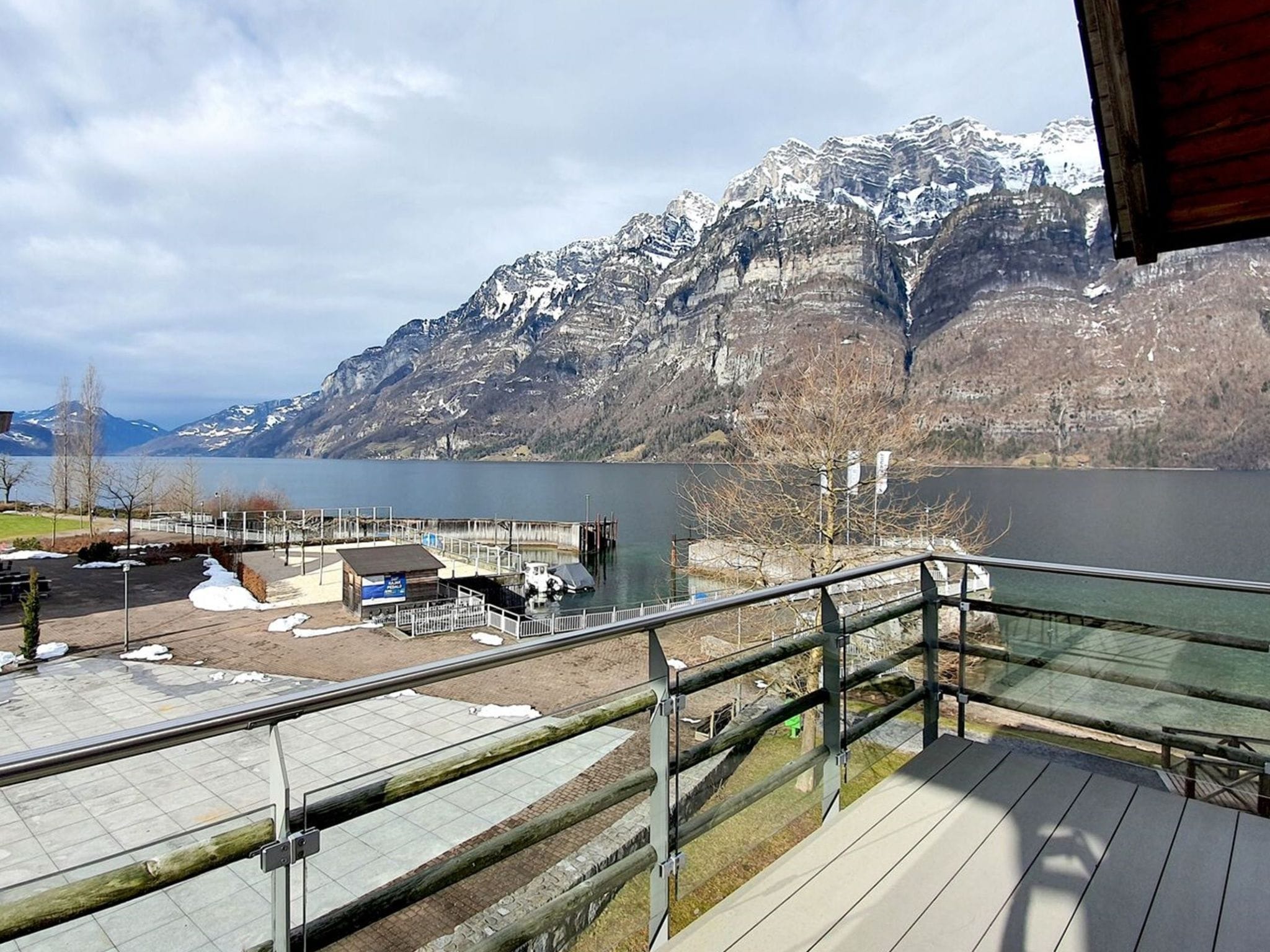 Een uitzicht op het meer met een houten terras, een steiger en een berg op de achtergrond.