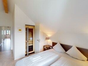 A hotel room with a bed, a nightstand, a lamp, and a wardrobe. - Walensee House & Apartments, (Unterterzen), by Interhome (Unterterzen)