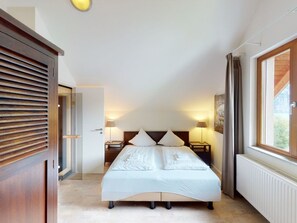 A bedroom with a bed, bedside tables, a window, and a door. - Walensee House & Apartments, (Unterterzen), by Interhome (Unterterzen)