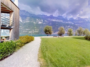 A pathway leading to a building with a mountain view, benches, and a grassy area.