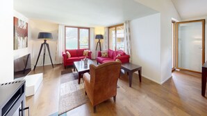 A spacious living area with a high ceiling, a red sofa set, a coffee table, and a floor lamp. - Walensee House & Apartments, (Unterterzen), by Interhome (Unterterzen)
