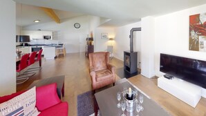 A modern living room with a fireplace, a dining area with red chairs, a kitchen in the background, and a flat-screen TV. - Walensee House & Apartments, (Unterterzen), by Interhome (Unterterzen)