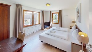 A hotel room with a bed, a desk, a chair, a TV, and a window with curtains. - Walensee House & Apartments, (Unterterzen), by Interhome (Unterterzen)