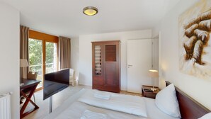 A hotel room with two beds, a desk, a chair, a wardrobe, and a painting on the wall. - Walensee House & Apartments, (Unterterzen), by Interhome (Unterterzen)